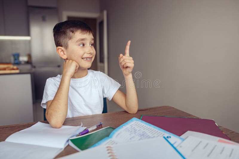 Nice cute Caucasian smart schoolboy showing number one 1 with finger at home. Homework.