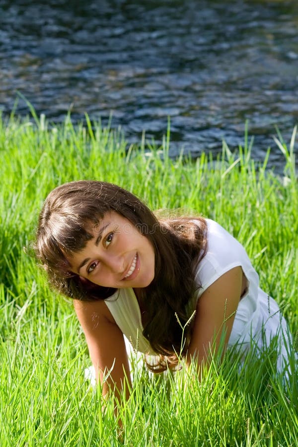 Nice girl on the grass near the river