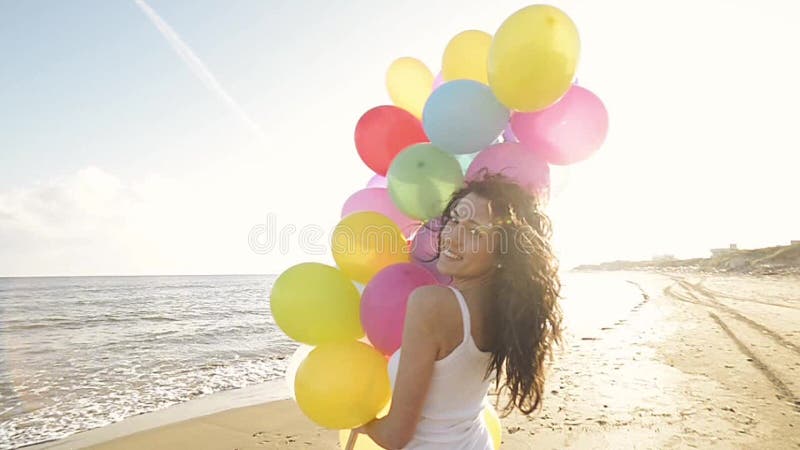 Nice girl playing with balloons on the beach