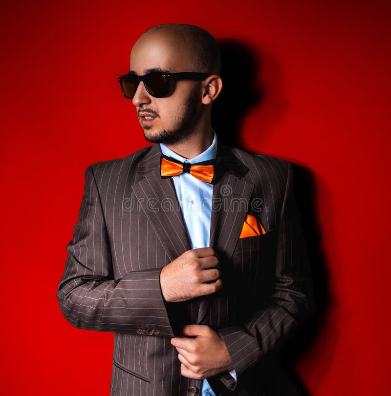 Nice man in sunglasses and suit on red background