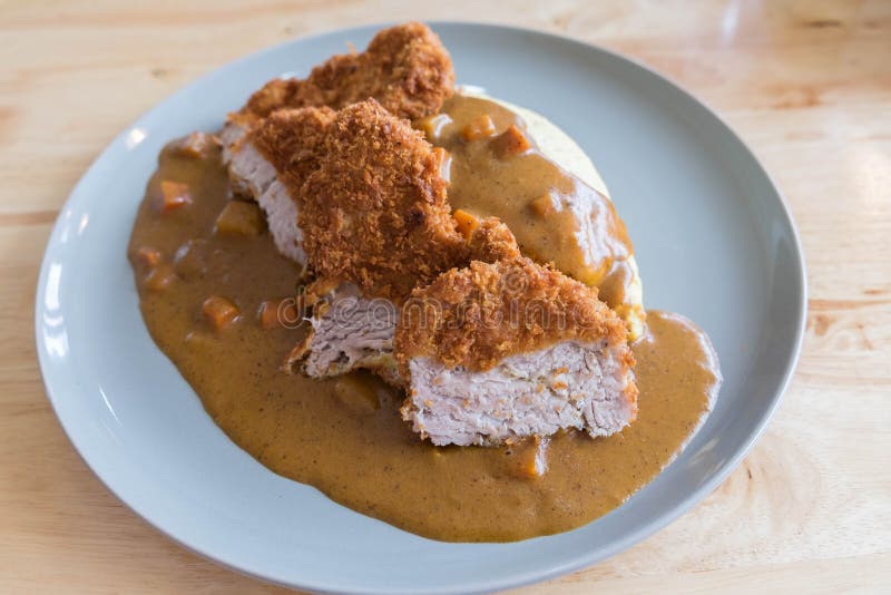 Omelette Rice with Japanese Curry and Breaded Deep Fried Pork Cutlet on Modern Wood Table royalty free stock images Omelette Rice with Japanese Curry and Breaded Deep Fried Pork Cutlet on Modern Wood Table royalty free stock images