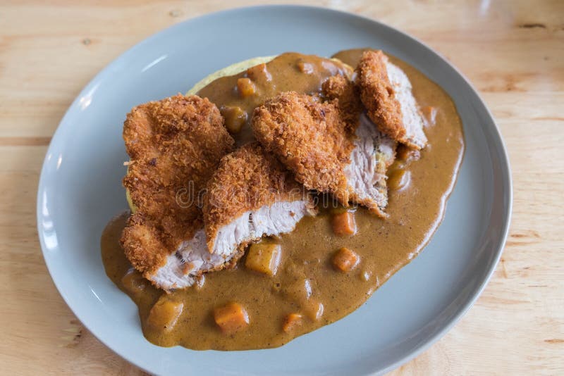 Omelette Rice with Japanese Curry and Breaded Deep Fried Pork Cutlet on Modern Wood Table stock photography Omelette Rice with Japanese Curry and Breaded Deep Fried Pork Cutlet on Modern Wood Table stock photography