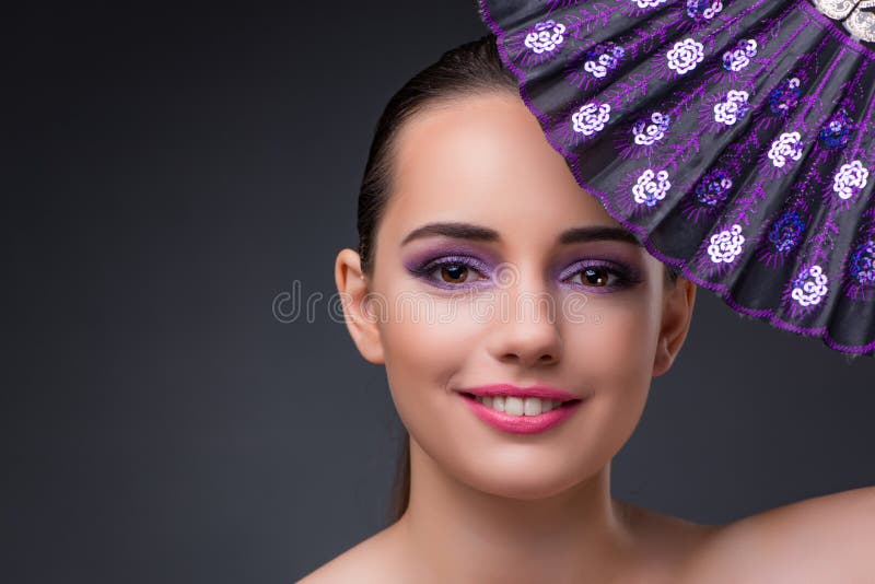 The nice woman with fan against gray background