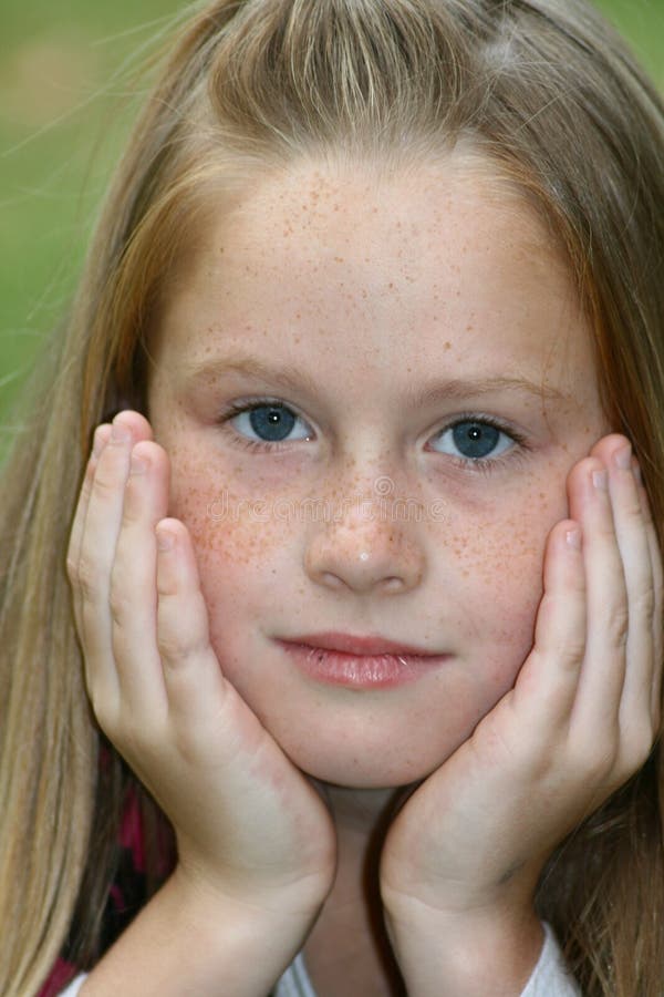 A white caucasian kid holding her head in her hands with a bored expression on her face. A white caucasian kid holding her head in her hands with a bored expression on her face
