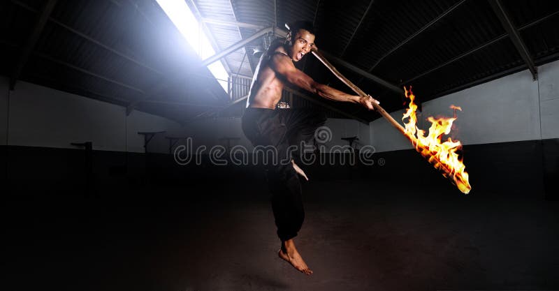 Martial arts kung fu master strikes with a burning stick in self defense. set in a training gym dojo, traditional dangerous sport fitness training. Large file, HDR composite panorama. Martial arts kung fu master strikes with a burning stick in self defense. set in a training gym dojo, traditional dangerous sport fitness training. Large file, HDR composite panorama