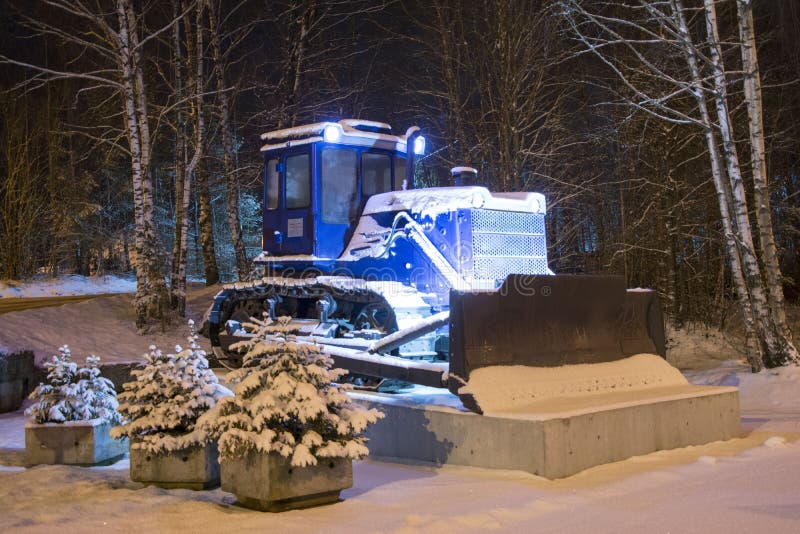 Niebieski ciągnik buldożerny na pedestale oświetlonym reflektorami obraz stock