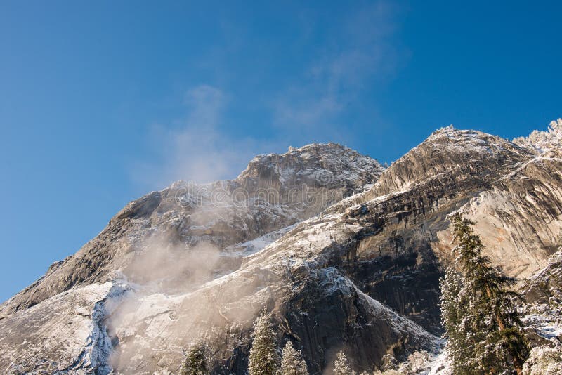 Niebla y nieve en árboles y acantilados del parque nacional de Yosemite, California en invierno durante salida del sol fotografía de archivo Niebla y nieve en árboles y acantilados del parque nacional de Yosemite, California en invierno durante salida del sol fotografía de archivo