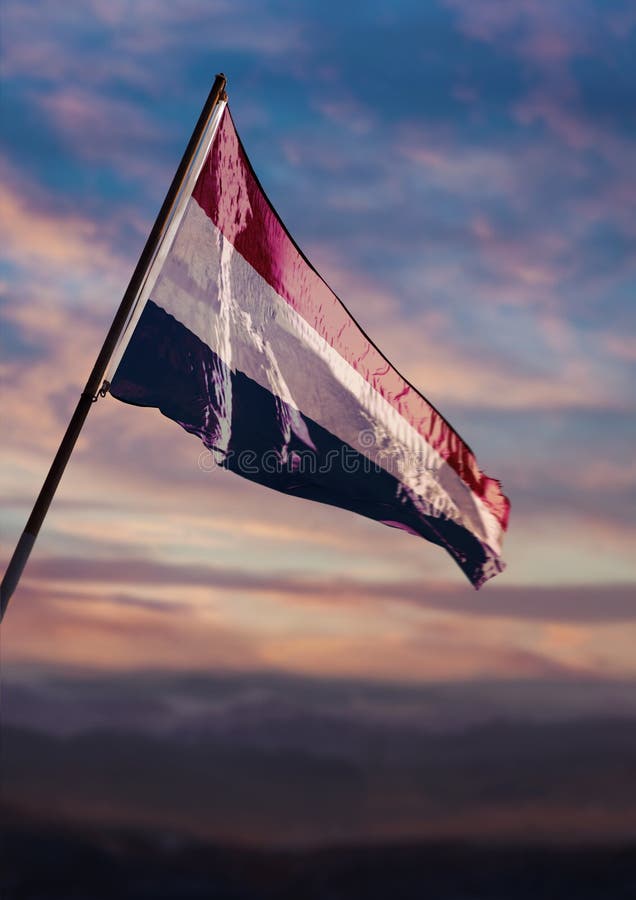 Niederländische Flagge, holländische Fahne wackelt in der Dämmerung am Himmel stockfotos