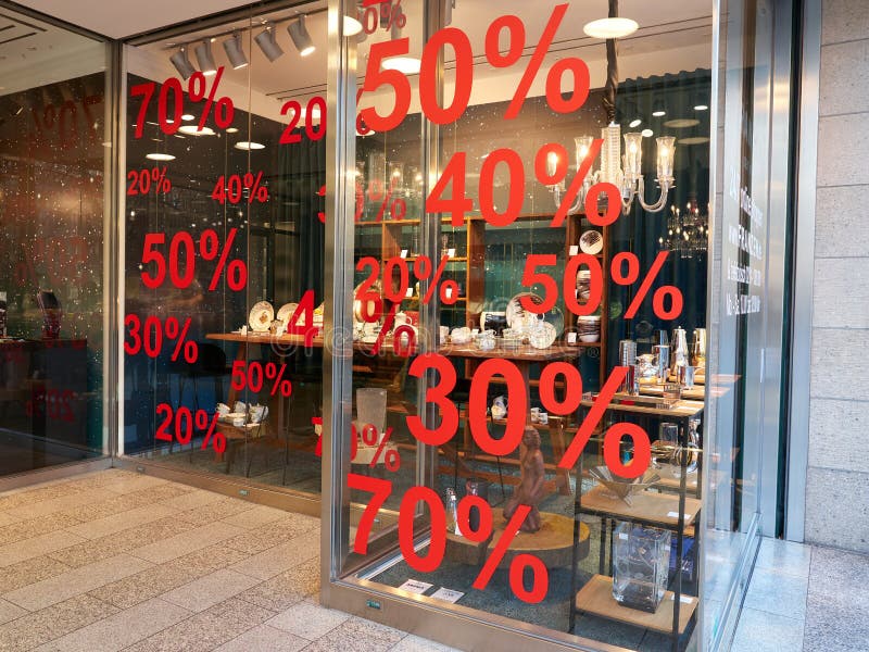 Dusseldorf, Germany - December 25, 2020: KÃ¶nigsallee shop window with red numbers informing about discount and promotion of 50, 30, 70 and 20 percent. Sale and discounting the assortment. Dusseldorf, Germany - December 25, 2020: KÃ¶nigsallee shop window with red numbers informing about discount and promotion of 50, 30, 70 and 20 percent. Sale and discounting the assortment