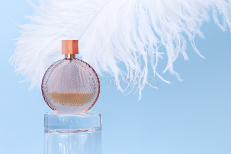 Nieoznakowana okrągła butelka perfum na szklanym podium i duże białe pióro strusie na niebieskim tle. przezroczyste perfumy szklan obrazy royalty free