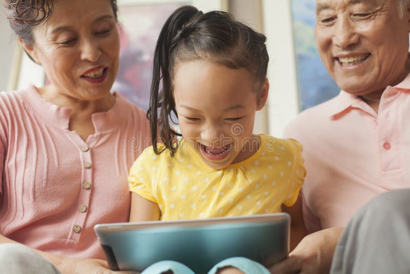 Nieta que juega en la tableta digital con los abuelos imagen de archivo libre de regalías