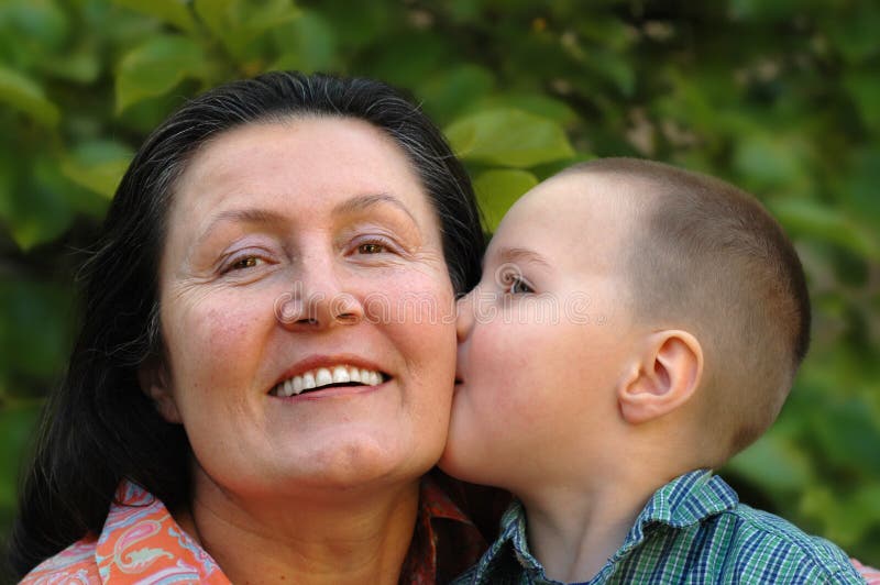 Young grandson giving his grandma a big smooch on the cheek. Young grandson giving his grandma a big smooch on the cheek