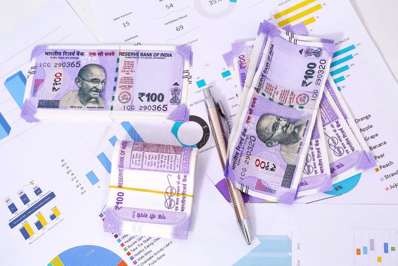 New Indian Currency notes with chart paper and pen. on wooden background. New Indian Currency notes with chart paper and pen. on wooden background.