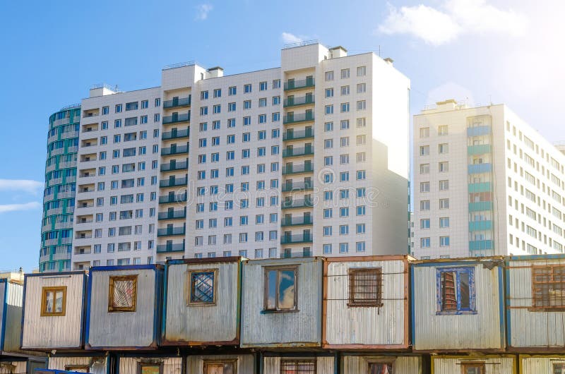 Nieuwe woongebouwen met meerdere verdiepingen, vóór hen barakken voor bouwersaanhangwagens Het concept urbanisatie, contrast royalty-vrije stock afbeeldingen Nieuwe woongebouwen met meerdere verdiepingen, vóór hen barakken voor bouwersaanhangwagens Het concept urbanisatie, contrast royalty-vrije stock afbeeldingen