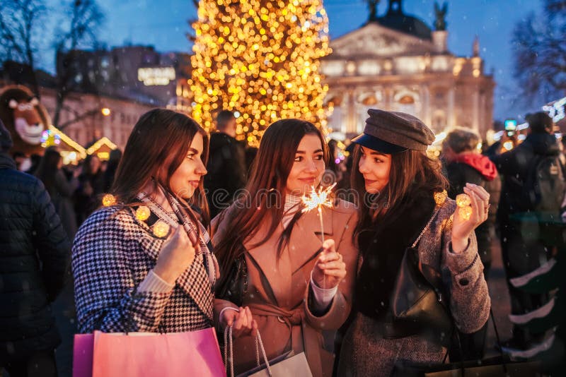 Nieuwjaarsconcept Vrouwelijke vrienden die in Lviv met kerstboomvuur op straat zonsopgang branden Meisjes met boodschappentas royalty-vrije stock afbeeldingen Nieuwjaarsconcept Vrouwelijke vrienden die in Lviv met kerstboomvuur op straat zonsopgang branden Meisjes met boodschappentas royalty-vrije stock afbeeldingen