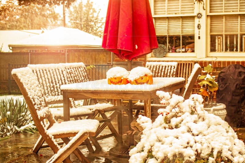 Nieve temprana - tabla y sillas al aire libre con dos linternas del enchufe o y un paraguas de sol en un patio durante una ducha fotografía de archivo libre de regalías Nieve temprana - tabla y sillas al aire libre con dos linternas del enchufe o y un paraguas de sol en un patio durante una ducha fotografía de archivo libre de regalías