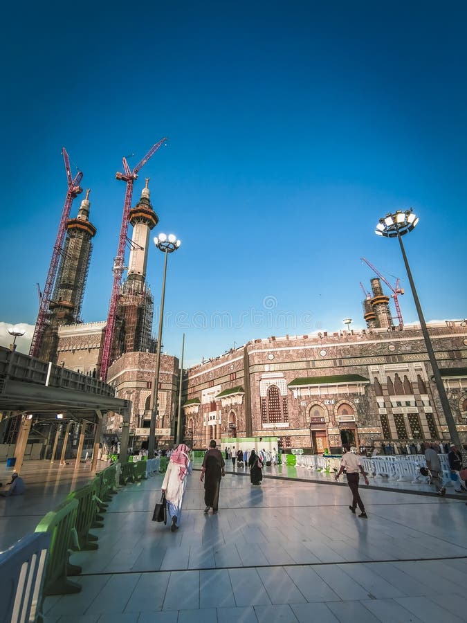 Niezidentyfikowani ludzie chodzą w stronę meczetu al haram w makkah saudi arabia z blues niebo w tle. zdjęcie stock