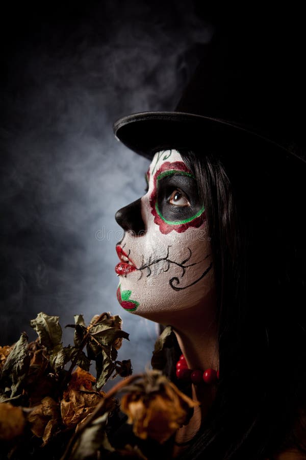 Sugar skull woman in tophat, holding dead roses, studio shot. Sugar skull woman in tophat, holding dead roses, studio shot