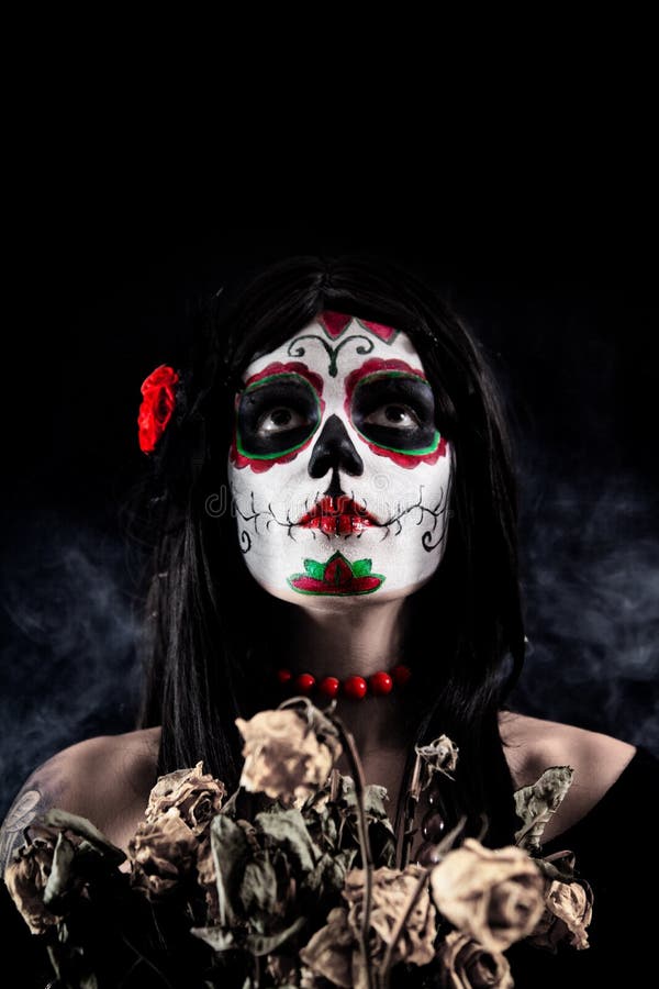 Sugar skull girl with dead roses, studio shot over black smoky background. Sugar skull girl with dead roses, studio shot over black smoky background