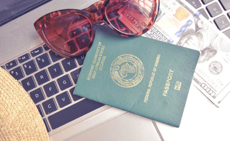 Nigerian Passport with US Dollar on keyboard of laptop with sunglasses