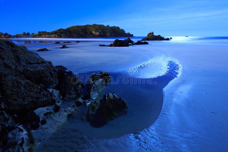 Night at the beach: tide pools and rocks illuminated by the moon