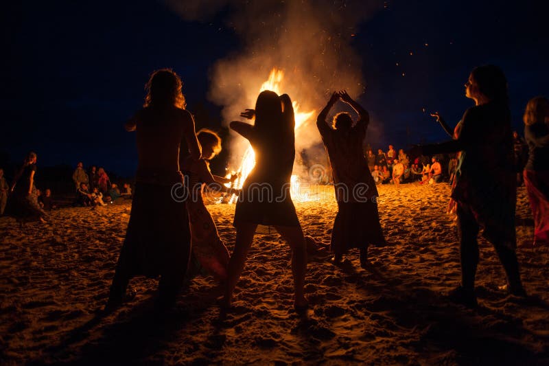 Night campfire. Leningrad Oblast, Russia - July 14, 2015: Big tourist bonfire on the beach Finland Gulf during the festival. Young people dance and sing around stock photography Night campfire. Leningrad Oblast, Russia - July 14, 2015: Big tourist bonfire on the beach Finland Gulf during the festival. Young people dance and sing around stock photography