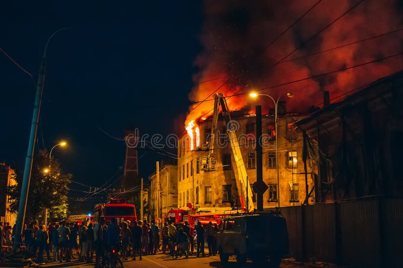Night fire in apartment building, firefighters struggle with flame, people stand around. Fire disaster and accident tragedy stock photos Night fire in apartment building, firefighters struggle with flame, people stand around. Fire disaster and accident tragedy stock photos