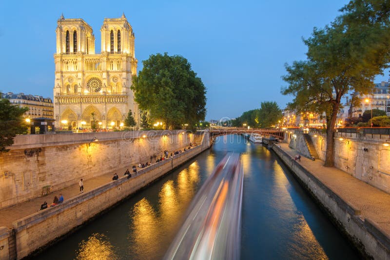 Dama París catedral a un rio por la noche.