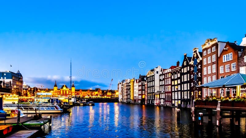 Night scene of the row of historic houses along the Damrak canal, dating back to the 18th century, in the center of Amsterdam royalty free stock photo Night scene of the row of historic houses along the Damrak canal, dating back to the 18th century, in the center of Amsterdam royalty free stock photo