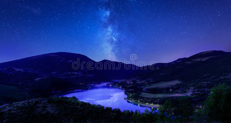 Night sky stars on mountain lake. Milky way reflections in dark