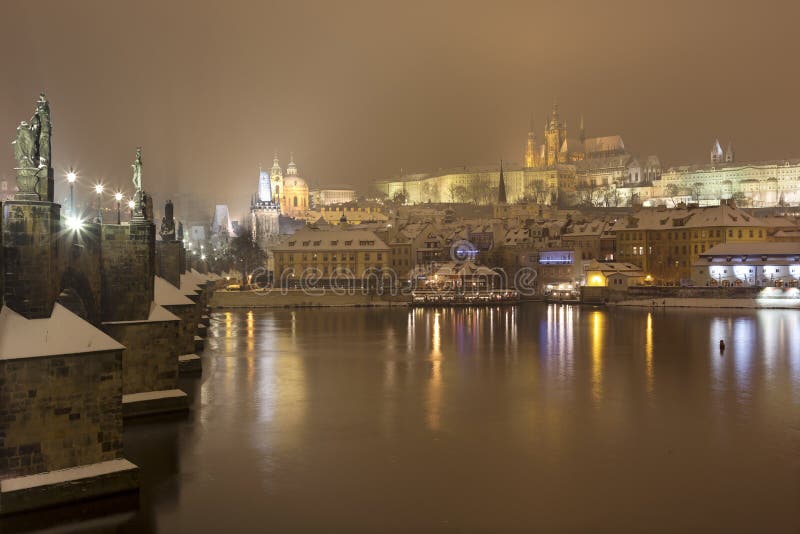 Night romantic snowy Prague gothic Castle with Charles Bridge and St. Nicholas' Cathedral , Czech republic