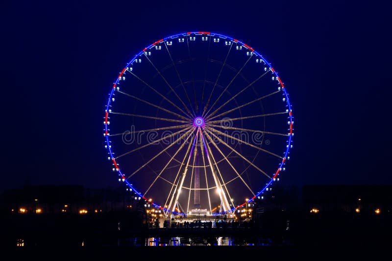 Pohľad na osvetlené a bez hnutia Veľké koleso z Place de la Concorde v Paríži, Francúzsku s obelisk v pozadí.