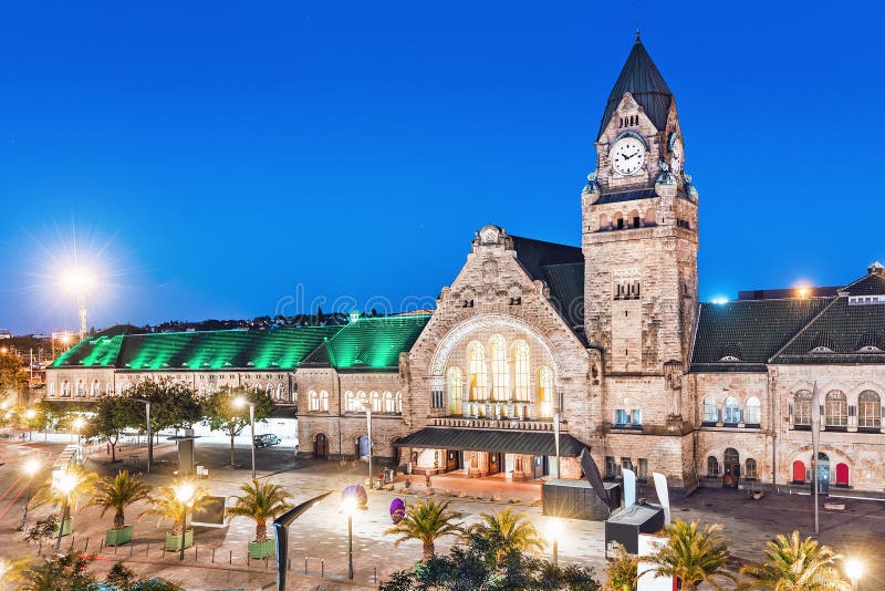view of the illuminated old railway station building with clock tower in Metz city