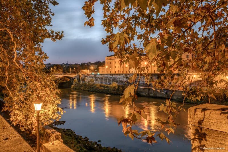 Night view of the river tevere in Rome. With a colorful sky and trees with autumn leaves under the yellow light of the street lanterns and lamp royalty free stock images Night view of the river tevere in Rome. With a colorful sky and trees with autumn leaves under the yellow light of the street lanterns and lamp royalty free stock images
