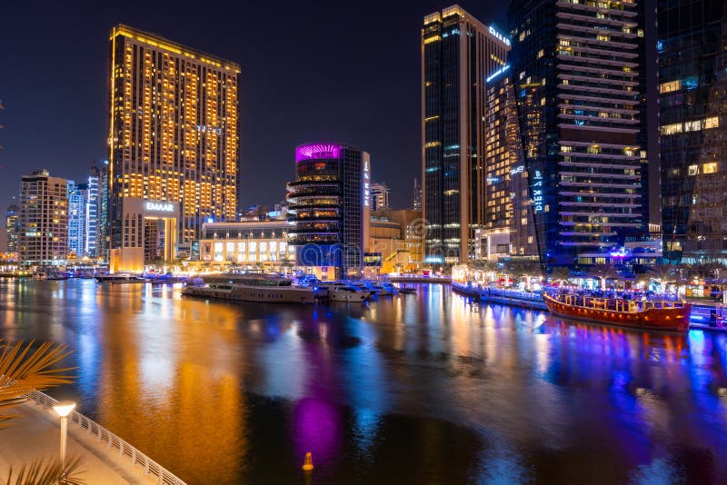 Night view to Dubai Marina panorama, reveals Pier 7 and boats. Luxury skyscrapers represent modern Dubai.