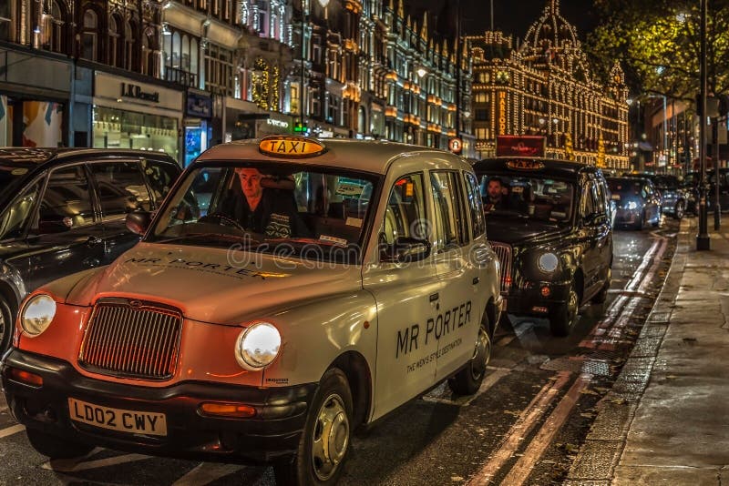 Night view with typical London taxis on moving in front of Harrods stock photography Night view with typical London taxis on moving in front of Harrods stock photography