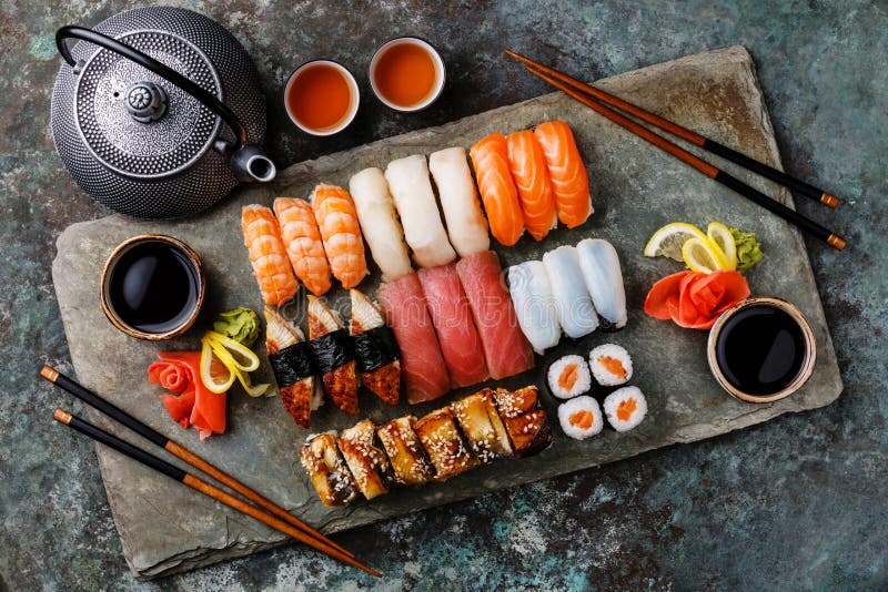 Nigiri dei sushi e rotoli di sushi stabiliti con tè per due immagine stock Nigiri dei sushi e rotoli di sushi stabiliti con tè per due immagine stock