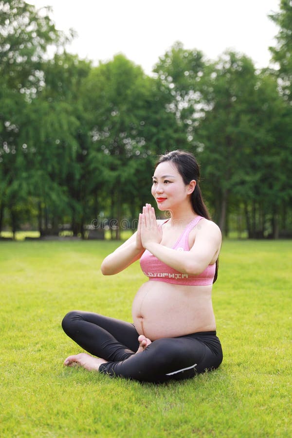 Asian Eastern Chinese young pretty pregnant girl woman do yoga sit in meditation, do lotus gesture of yoga over sunset,namaste. Nike logo was removed, and I stock photo Asian Eastern Chinese young pretty pregnant girl woman do yoga sit in meditation, do lotus gesture of yoga over sunset,namaste. Nike logo was removed, and I stock photo