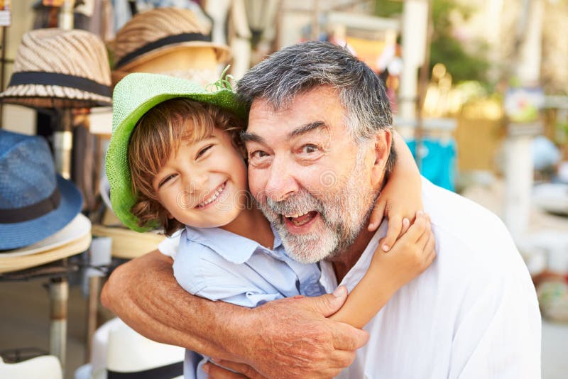 Nipote che prova sui cappelli con il nonno al deposito immagine stock libera da diritti Nipote che prova sui cappelli con il nonno al deposito immagine stock libera da diritti