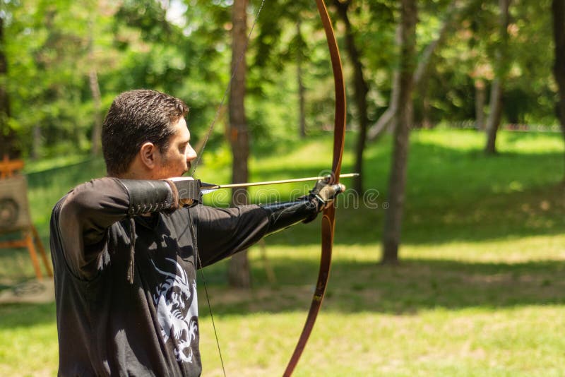 Archer with bow shoot arrow in the forest on knight festival in a traditional suit stock photography Archer with bow shoot arrow in the forest on knight festival in a traditional suit stock photography
