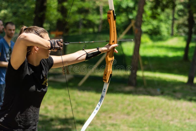Professional girl archer with bow shoot arrow in the forest on knight festival and tournament stock photo Professional girl archer with bow shoot arrow in the forest on knight festival and tournament stock photo