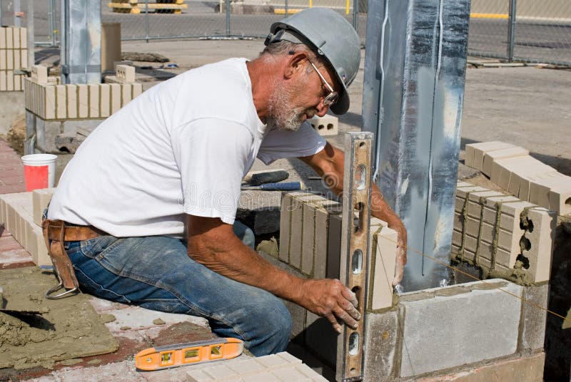 Bricklayer checking the level of vertical bricks, also known as soldiers, as he lays them. Bricklayer checking the level of vertical bricks, also known as soldiers, as he lays them.