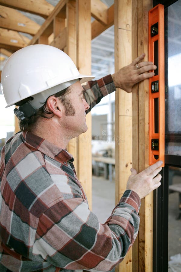 A construction worker checking that a newly installed window is level. Vertical view. Authentic and accurate content. A construction worker checking that a newly installed window is level. Vertical view. Authentic and accurate content.