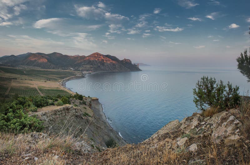 Nivelando o crepúsculo em uma baía quieta no pé das montanhas fotografia de stock Nivelando o crepúsculo em uma baía quieta no pé das montanhas fotografia de stock
