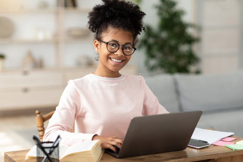 Niña adolescente negra en laptop aprendiendo en línea sentada en casa fotos de archivo libres de regalías
