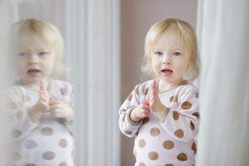 Adorable little girl with milk moustache standing by the window. Adorable little girl with milk moustache standing by the window