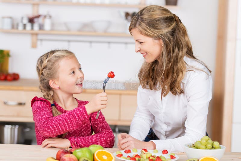 Adorable niña pequeña alimentando a su madre fotos de archivo