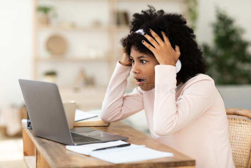 Niña africana en un portátil con problemas de conexión a internet en casa imagenes de archivo