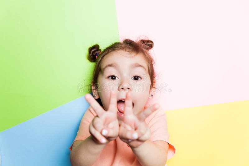 Niña bastante de cuatro años con la cara divertida en fondo multicolor Colores brillantes y imagen elegante foto de archivo libre de regalías Niña bastante de cuatro años con la cara divertida en fondo multicolor Colores brillantes y imagen elegante foto de archivo libre de regalías