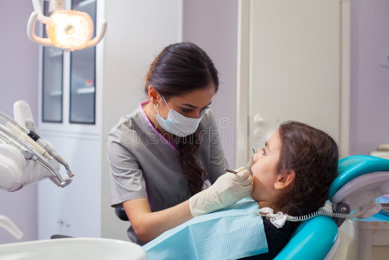 Niña bonita que abre el suyo boca de par en par durante tratar sus dientes del dentista imagenes de archivo Niña bonita que abre el suyo boca de par en par durante tratar sus dientes del dentista imagenes de archivo